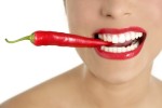 Beautiful woman teeth eating red pepper