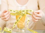 Woman tying measuring tape around glass of beer