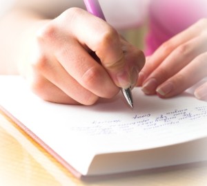 Young female is writing notes and planning her schedule.