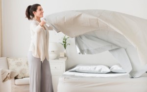 USA, New Jersey, Jersey City, Woman spreading sheet on bed