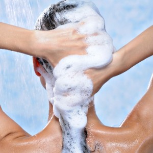 washing long brunette female hair by shampoo