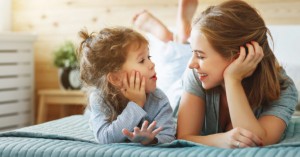 Happy family mother and child daughter laughing in bed