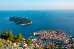 Pogled na stari grad Dubrovnik s povijesnim zidinama i Jadranskim morem u pozadini.